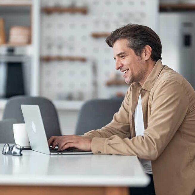 Mann arbeitet am Laptop in der Küche