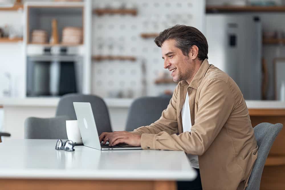 Mann arbeitet am Laptop in der Küche