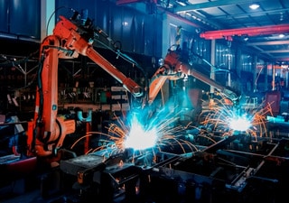 Industrieroboter schweißen in Fabrikhalle bei Nacht