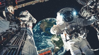 Astronauten arbeiten im All mit Erde im Hintergrund.