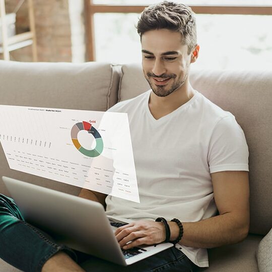 Mann analysiert Daten am Laptop auf Sofa